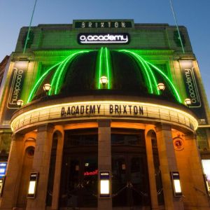 Brixton Academy, live music venue in London, lit up with green in twilight.